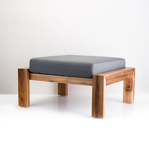 A warm brown wood Aegean Stool with light grey fabric upholstery